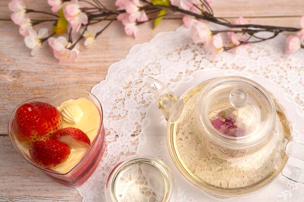 Tarta de queso con mousse de fresa servida con té de hierbas caliente con flor rosa en el interior