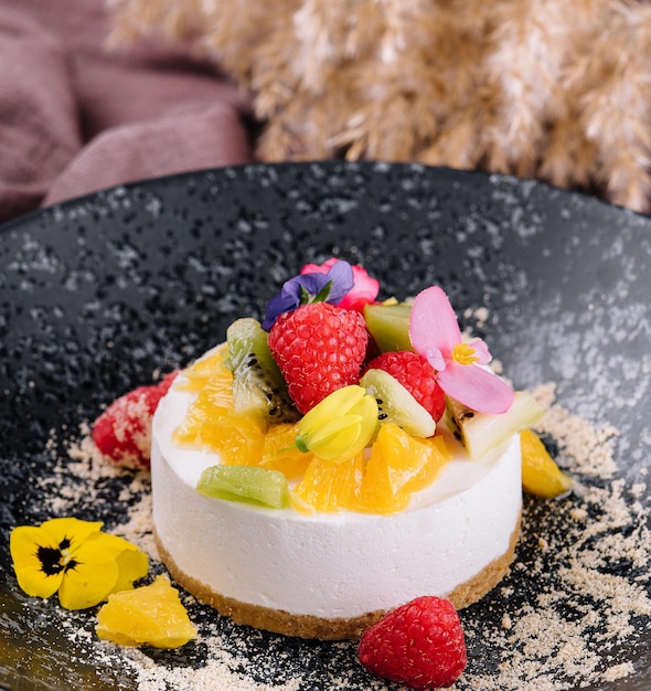 Tarta de queso redonda con decoración de frutas y taza de café.