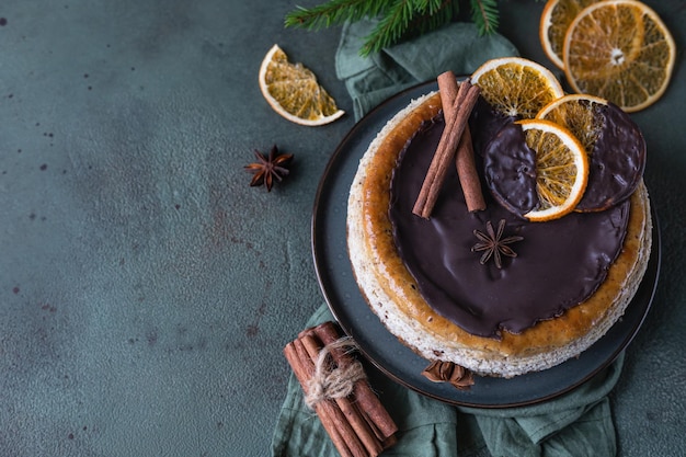 Tarta de queso con rodajas de naranjas secas, canela y anís decoradas con chocolate