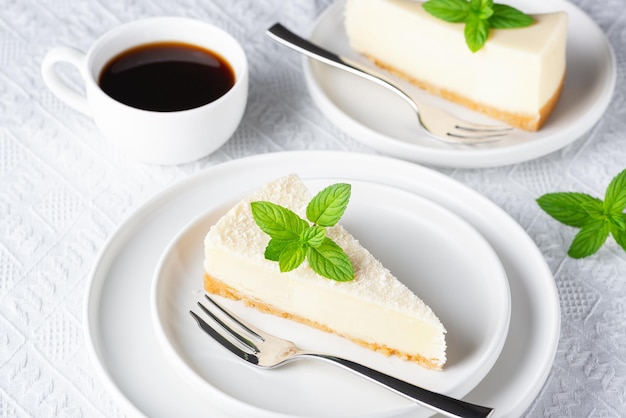 Tarta de queso y taza de café negro sobre una mesa blanca