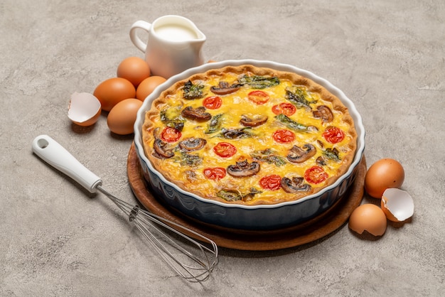 Tarta de quiche casera al horno en forma de cerámica para hornear, huevos y crema