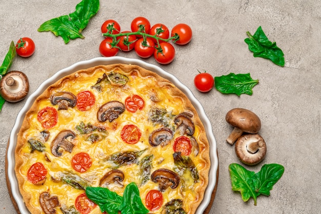 Tarta de quiche casera al horno en forma de cerámica para hornear sobre fondo de hormigón