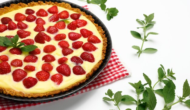 Tarta redonda al horno con fresas y crema de leche tierna sobre un fondo de mesa blanco, vista superior