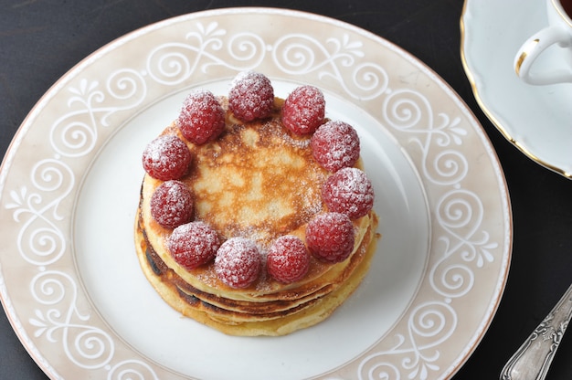 Tarta redonda con frambuesas y taza de té