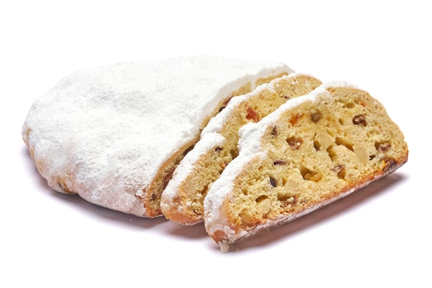 Tarta stollen de Navidad tradicional en rodajas con mazapán y frutos secos aislado sobre fondo blanco.