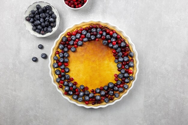 Tarta de tarta de queso delicioso con arándanos frescos y arándanos, sobre un fondo de hormigón claro.