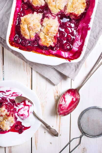 Tarta de zapatero de cereza casera con corteza hojaldrada, helado, cuchara vintage