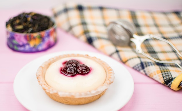 Tartaleta con bayas y crema en un plato blanco sobre un fondo de madera rosa