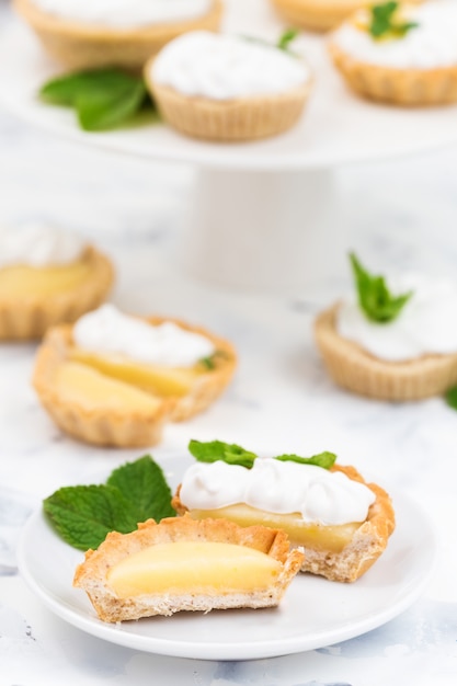 Tartaletas caseras de cuajada de limón con merengue, hojas de menta y flores.