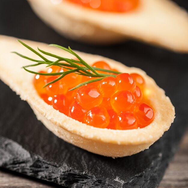 Tartaletas con caviar rojo sobre piedra negra