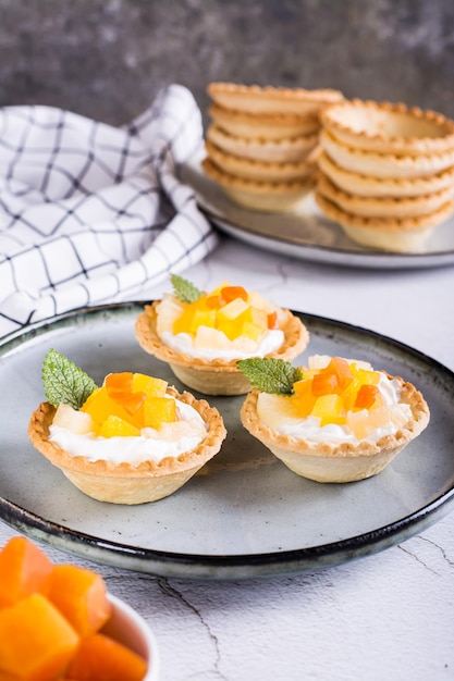 Tartaletas con crema batida y piña enlatada y papaya en una vista vertical de la placa