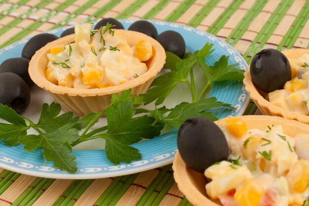 Tartaletas con ensalada y aceitunas en una placa azul.