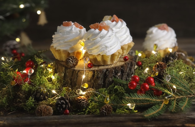 Tartaletas festivas con crema sobre un fondo oscuro con abeto y luces