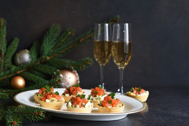 Tartaletas rellenas de ensalada y salmón en una mesa de Año Nuevo. Mesa festiva con una copa de champán