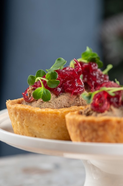 Tartaletas rellenas de hígado de bacalao, caviar de bacalao y microgreens Aperitivo tradicional en porciones frías en una cesta de pastelería