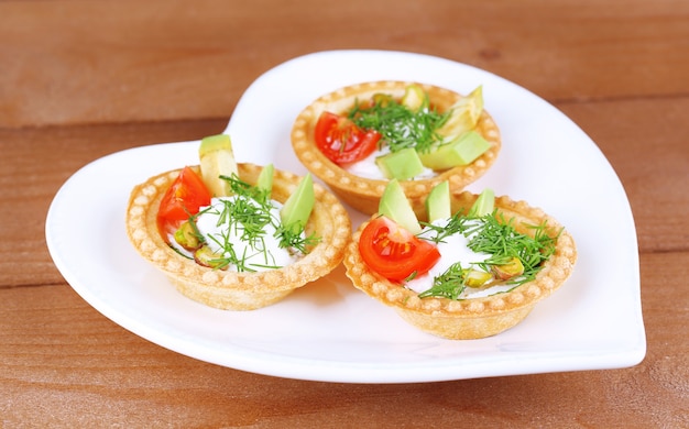 Tartaletas con verduras y verduras con salsa en un plato sobre la mesa