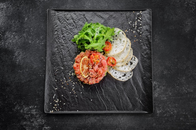 Tartar de salmón con aguacate en una placa negra