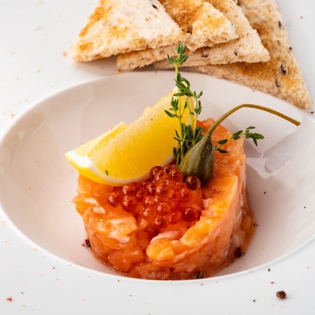 Tartar de salmón con alcaparras, limón y caviar rojo.