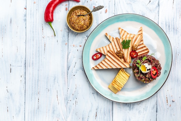 Tartar de ternera con alcaparras, pepino encurtido y huevo de codorniz crudo con tostadas de pan