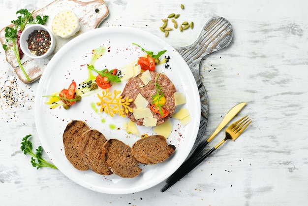 Tartar de ternera con pan tostado y verduras en un plato blanco Vista superior Estilo rústico