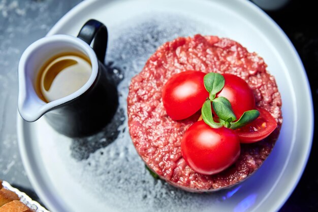 Tartar de ternera con tomates en un plato blanco en un restaurante