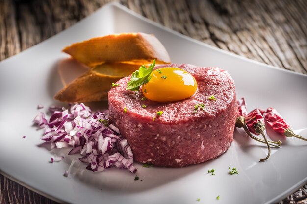 Tartar de ternera con yema de huevo, cebolla morada, ají, hierbas y bruschetta.