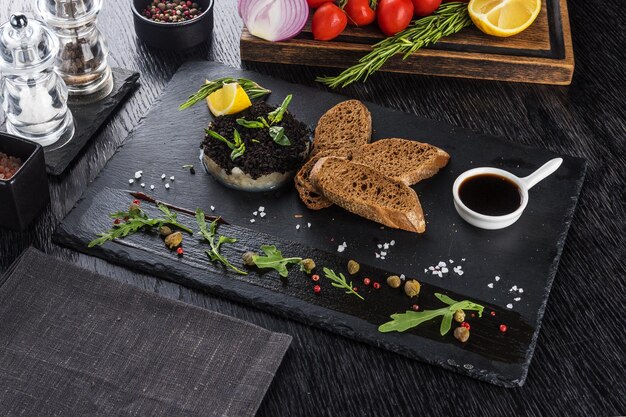 Foto tartare de vieiras em uma bandeja de pedra preta