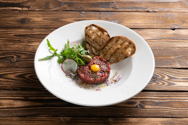 Tártaro de carne marinado com ovo de codorna, salada de rúcula, rabanete, alcaparras e ciabatta grelhada