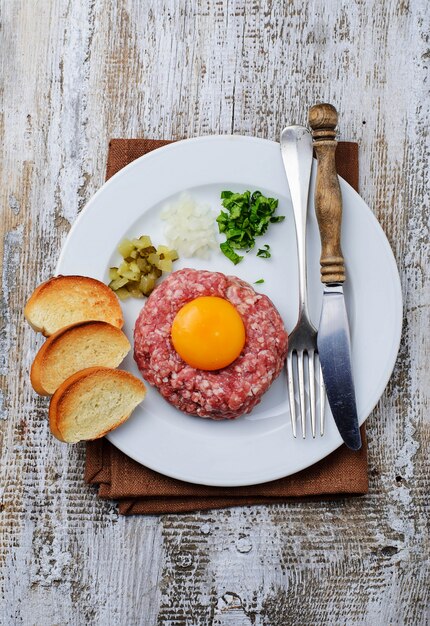 Tártaro fresco da carne com ovo, o pepino conservado e a cebola.