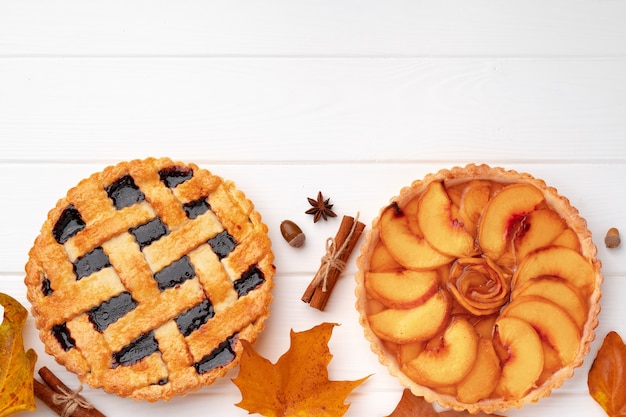 Tartas de Acción de Gracias en tablero de madera blanca decorada con hojas secas y palitos de canela