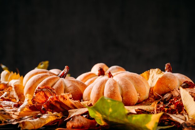 Tartas caseras en forma de calabaza y hojas de otoño en la oscuridad con espacio de copia. Cocinar para Halloween