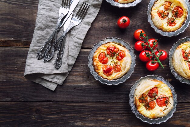 Tartas caseras frescas con tomates cherry y queso de cabra sobre fondo de madera rústica. Vista superior.