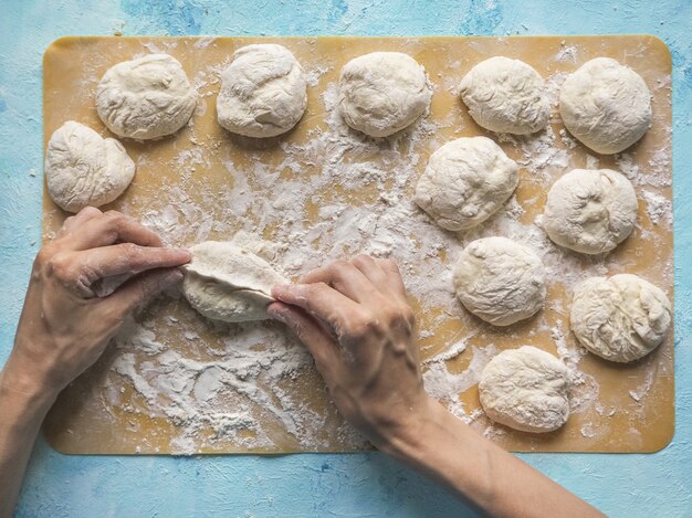 Foto tartas caseras de la masa en manos de las mujeres. el proceso de hacer pasteles con masa de repollo a mano.