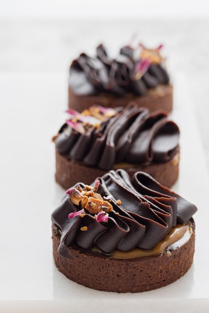 Tartas de chocolate decoradas con ganache de chocolate oscuro sobre un fondo blanco