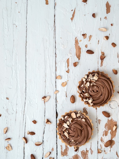 Las tartas de chocolate se sirven con nueces de almendra en la superficie de madera blanca en mal estado