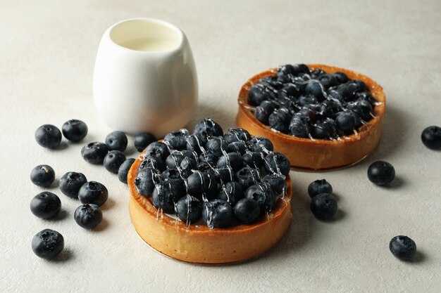 Tartas de leche y arándanos en mesa gris