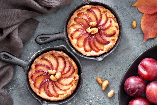 Tartas de migajas caseras con rodajas de ciruela al horno en pequeñas sartenes de hierro