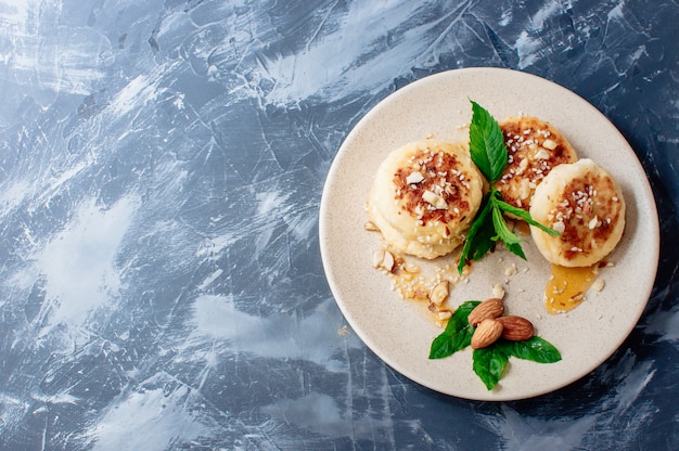 Tartas de queso con almendras menta fresca y jarabe de arce sobre un fondo gris de una mesa de hormigón.