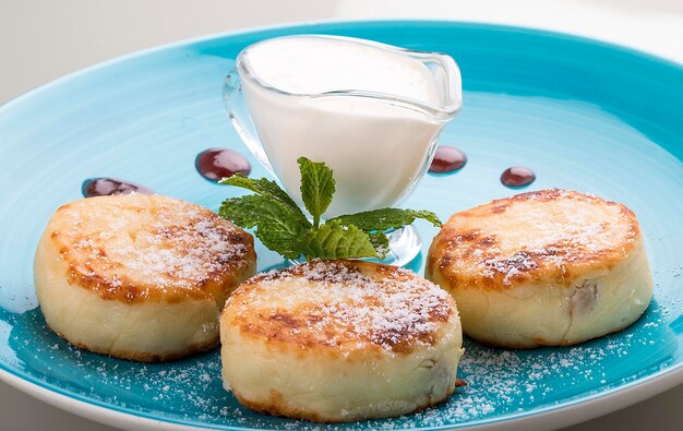 Tartas de queso de desayuno con crema agria en un plato azul