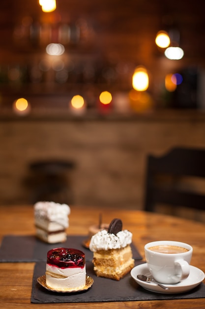 Tartas variadas de postre sobre una mesa de madera en una cafetería. Tartas con ingredientes naturales. Deliciosa taza de café. Tartas con diferentes sabores.