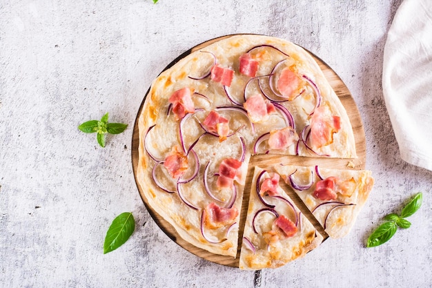 Tarte francesa flammkuchen com cream cheese, cebola e bacon em uma placa em cima da mesa Vista superior