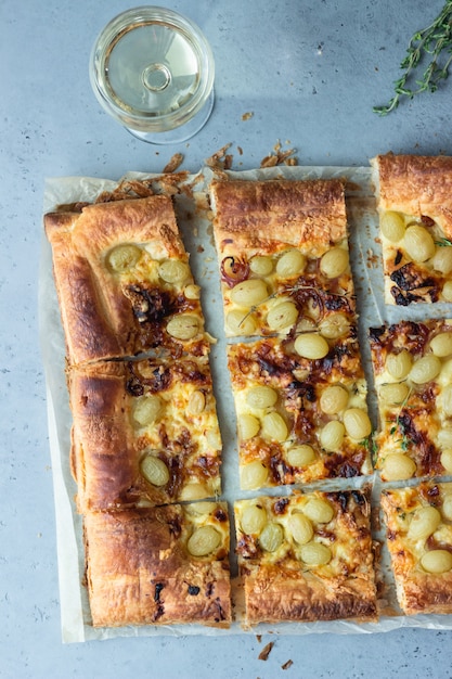 Tarte mit Blätterteig, karamellisierten Zwiebeln, Käse, Thymian und grünen Trauben