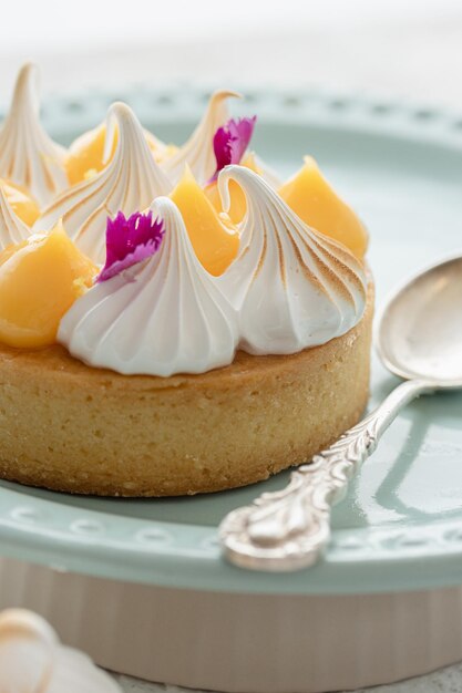 Tartella de limón decorada con merengues y pétalos de flores Tarta de limón servida en un plato con una cuchara