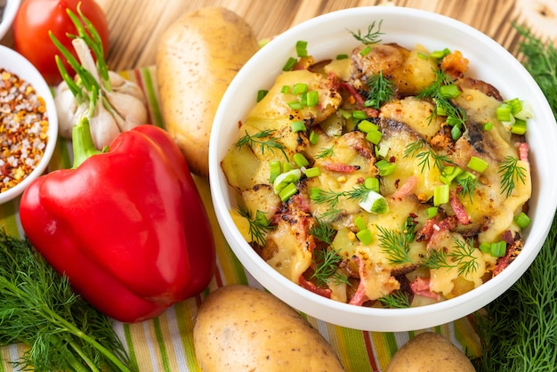 Tartiflette com legumes e bacon em uma mesa de madeira. Vista do topo.