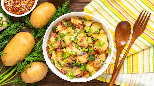 Tartiflette tradicional con tocino, hierbas y verduras sobre mesa de madera. Vista superior.