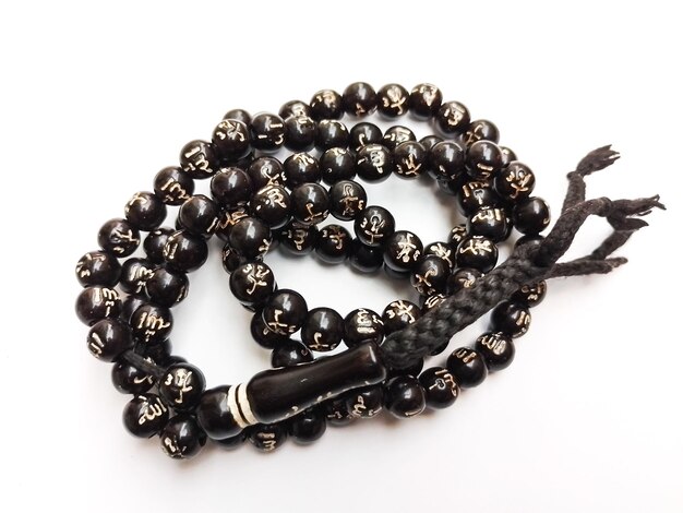 Foto un tasbih de cuentas negras está en una superficie blanca