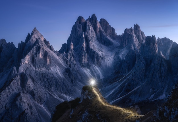 Taschenlampenspuren auf Bergpfad gegen hohe Felsen bei Nacht