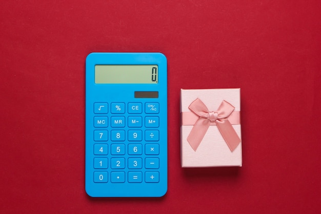 Taschenrechner und Geschenkboxen mit Schleife auf Rot. Berechnung des Wertgeschenks.