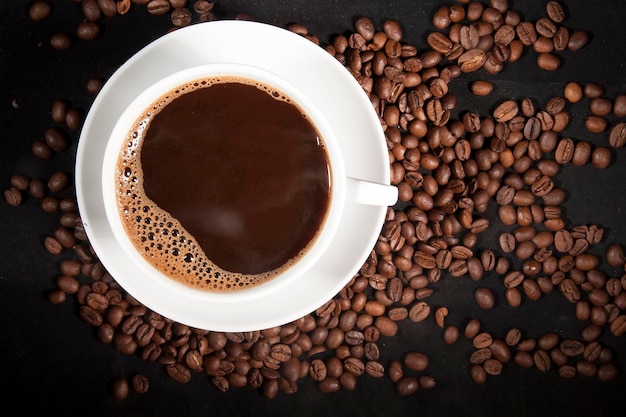 Tasse aromatischer Kaffee mit Kaffeebohnen auf dunklem Hintergrund