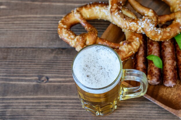 Tasse Bier mit Bratwürsten und Brezeln.